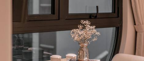 A round wooden table with a vase of flowers, a mug, and books.