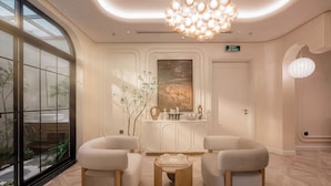A modern lobby with two sofas, a wooden coffee table, a decorative cabinet, and a large window with a view of greenery. -  iRest Atelier Hanoi Apartment & Hotel (Hanoi)