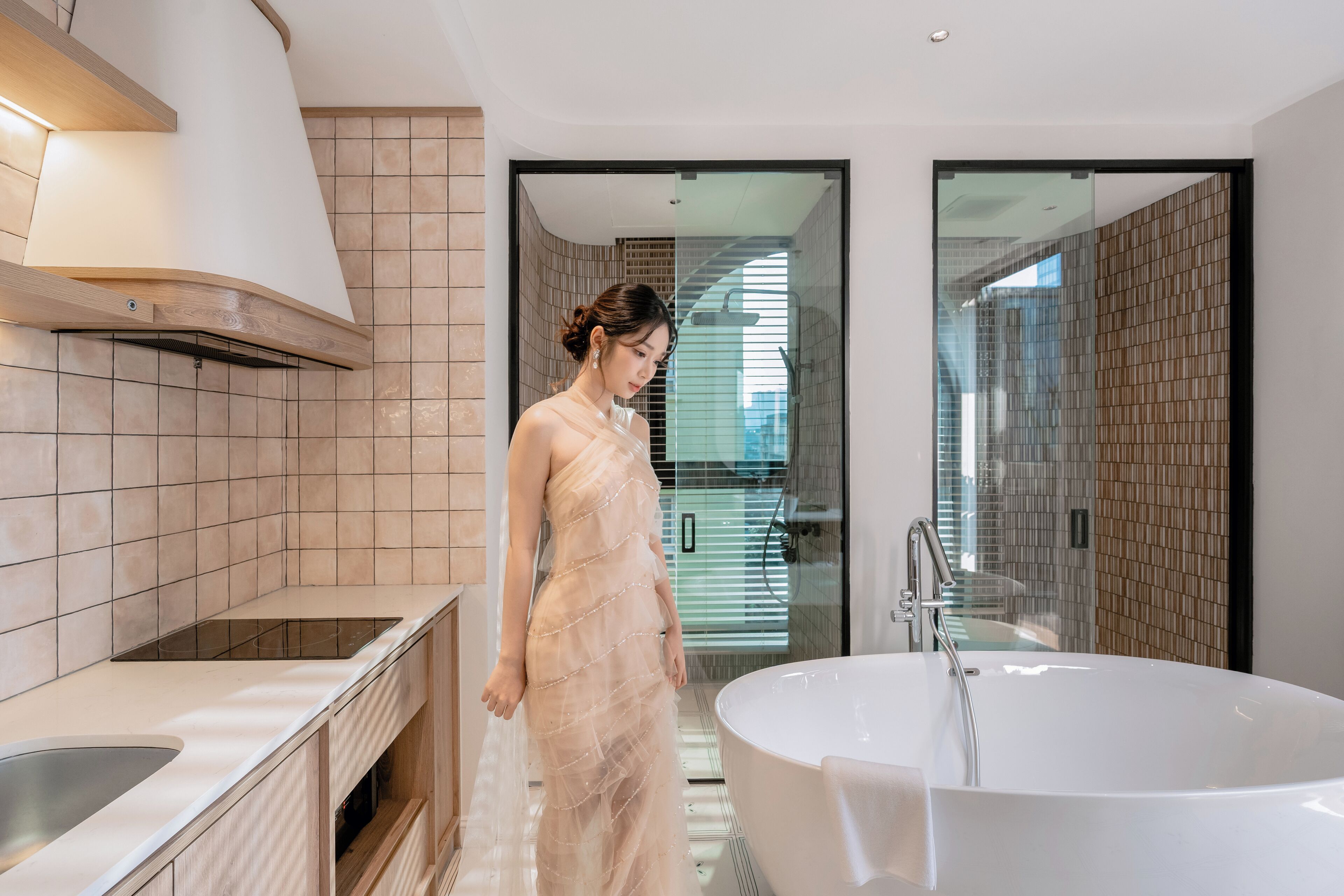A modern bathroom with a large bathtub, a glass shower enclosure, and a kitchen area with a stove and sink.