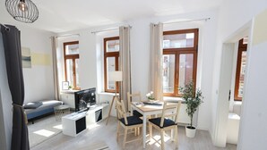A modern living room with a sofa, TV, dining table, chairs, and a potted plant. - FullHouse | Chemnitz | M45-2 | Studio (Chemnitz)