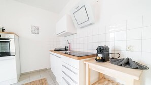 Et moderne køkken med hvide skabe, en sort bordplade og en kaffemaskine.
