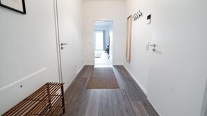 A hallway with a wooden bench, a rug, and a door with a sign. - FULL HOUSE Premium Apartment Dresden (Dresden)