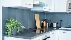 A modern kitchen with white cabinets, a black countertop, and a built-in stove. - FULL HOUSE Premium Apartment Dresden (Dresden)