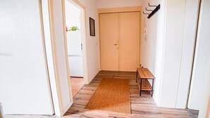 Un pasillo con suelo de madera, un banco y una puerta.