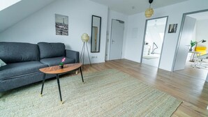 A modern living room with a grey sofa, a wooden coffee table, and a large mirror. - FullHouse | Magdeburg | L10-5 | RoofTop (Magdeburg)