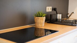 Et køkken med en sort bordplade, en vævet plantekasse og en kaffemaskine.