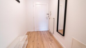 En gang med en hvid dør, en radiator og et spejl på væggen.
