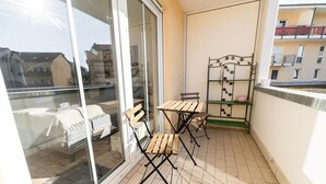 En balkon med to træstole og en metalkonstruktion med hylder.