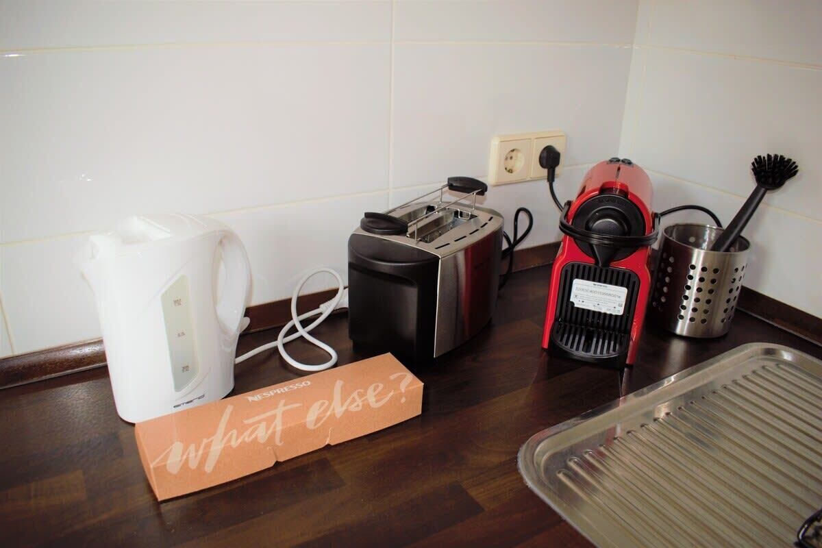 A kitchen with a coffee maker, toaster, red espresso machine, and a tray.
