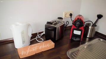 A kitchen with a coffee maker, toaster, red espresso machine, and a tray.