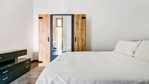 Ein Schlafzimmer mit einem großen Bett, einem Holzschrank und einem dunklen Konsolentisch.