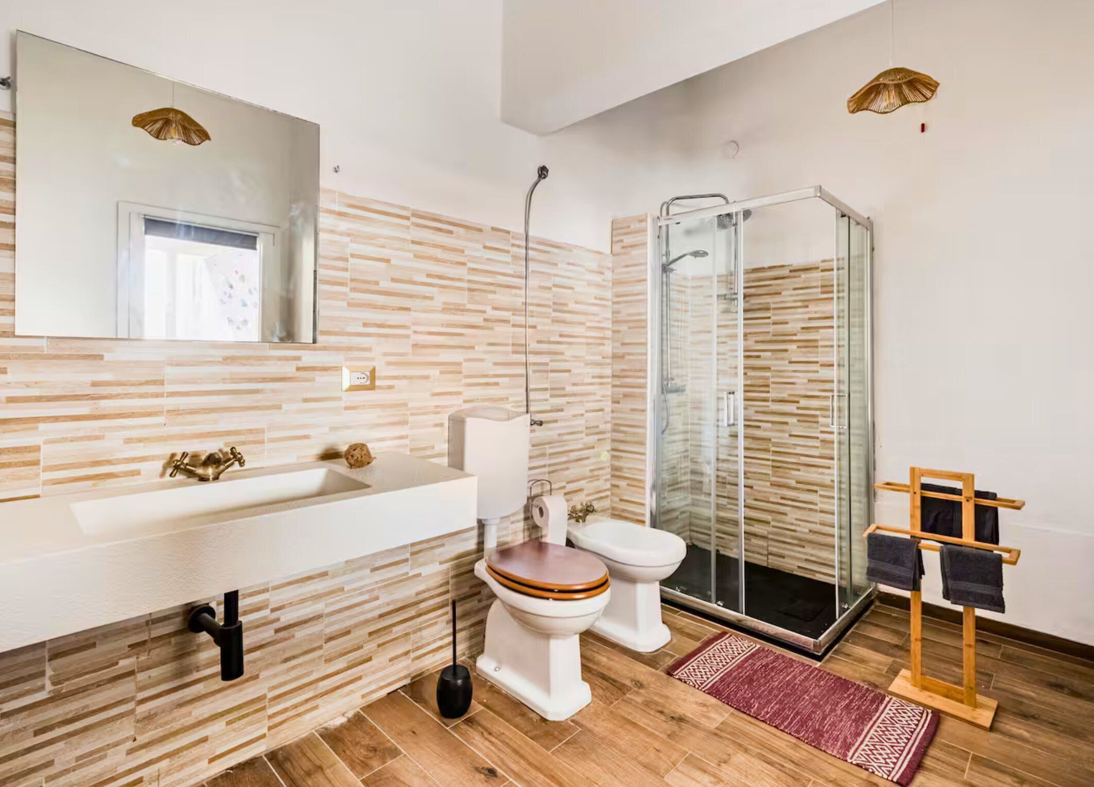 A modern bathroom with a large mirror, a sink, a toilet, and a glass-enclosed shower.