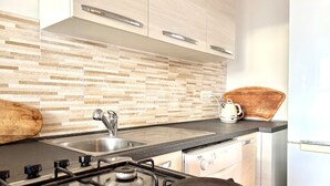 Eine moderne Küche mit einem Gasherd, einer Edelstahl-Spüle und einem Holztisch zum Schneiden auf der Arbeitsplatte.