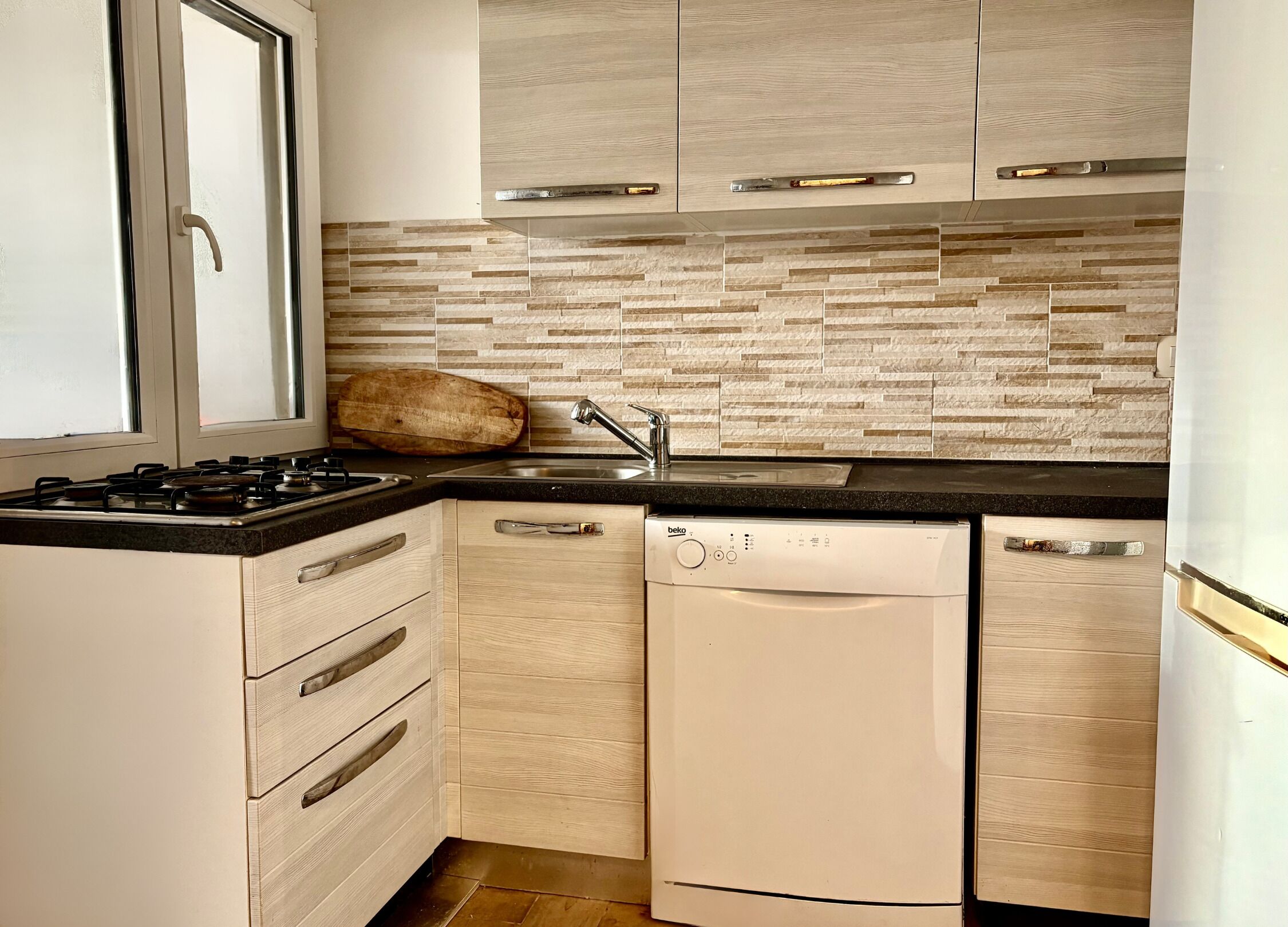 A modern kitchen with a gas stove, dishwasher, and wooden cabinets.