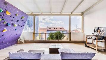 A balcony with a climbing wall, wicker furniture, and a view of buildings.