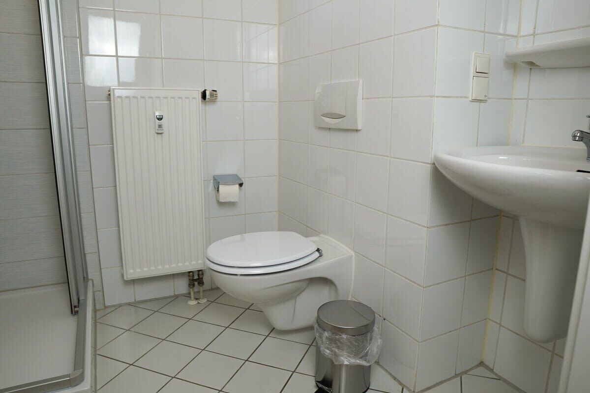 Un bany amb vàter, un lavabo, un safata d'escombraries i un radiador.