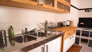 A modern kitchen with stainless steel sinks, a wooden countertop, and white cabinetry. - FullHouse | Halle | T28 Panda Apt. (Halle (Saale))
