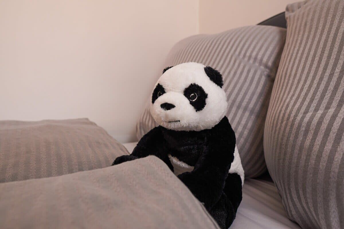 A plush panda toy sitting on a striped couch.