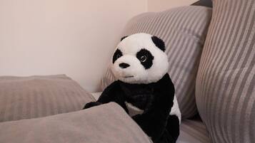A plush panda toy sitting on a striped couch.