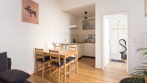 Cozinha moderna com armários brancos, uma mesa de jantar de madeira e cadeiras. Há um quadro de um alce na parede.