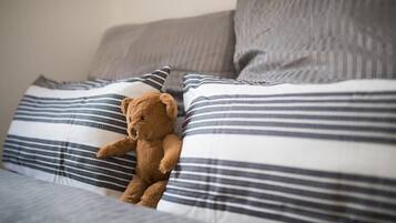 A bed with striped bedding and a teddy bear.