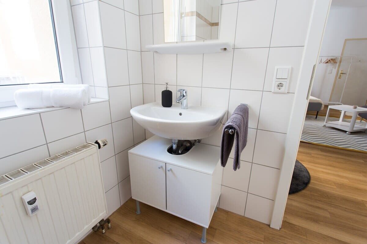 Et moderne badeværelse med en hvid vask, et spejl over vasken og en håndklædestang.