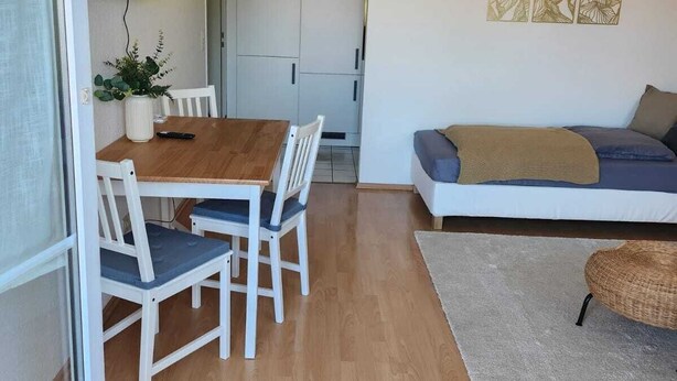 Un soggiorno moderno con zona pranzo, divano e televisione a parete.