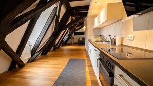 Une cuisine moderne avec des poutres apparentes, un plan de travail noir et un four encastré.