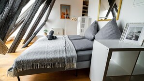 Une chambre à coucher moderne avec un lit en mezzanine, une table de chevet, un miroir et un tableau encadré.