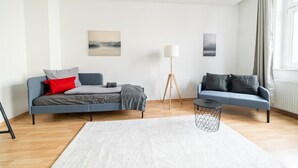 A modern living room with two sofas, a standing lamp, and a small round table.