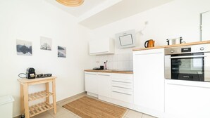 A modern kitchen with white cabinets, a built-in oven, and a coffee machine.