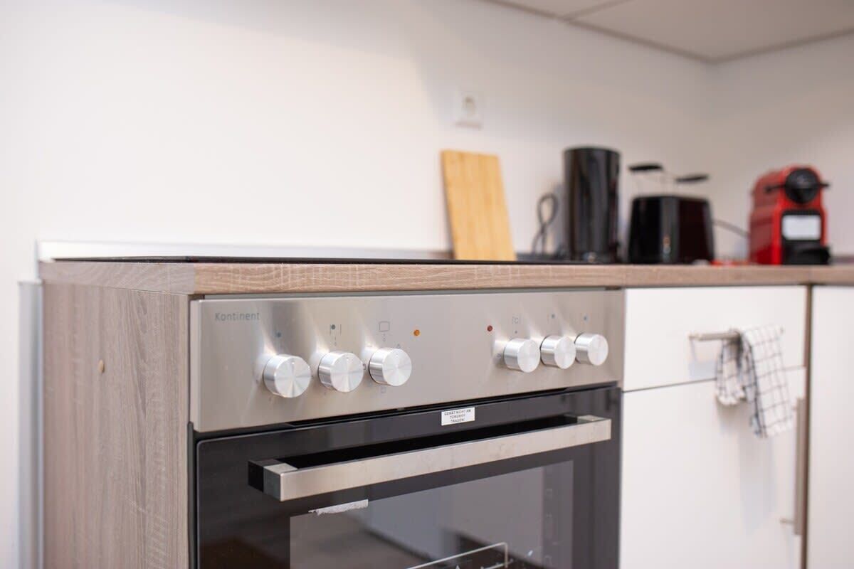 Una cocina moderna con estufa de acero inoxidable, horno empotrado y encimera de madera.