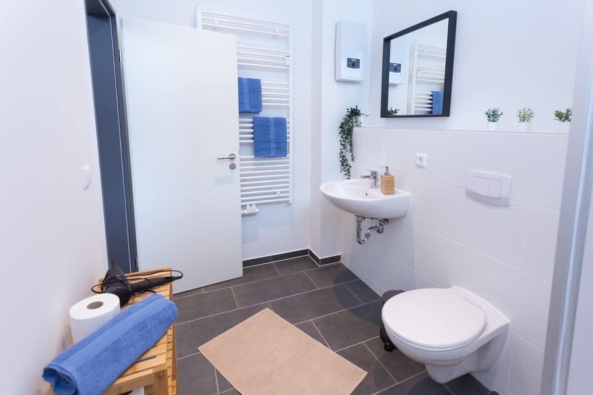 A bathroom with a white sink, a toilet, a towel rack, and a mirror.