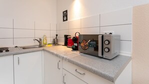 Eine Küche mit weißen Schränken, einer Granitabdeckung, einer Kaffeemaschine, einem Toaster und einer Wandleuchte.