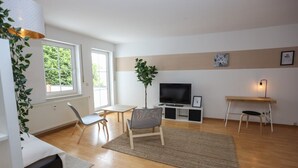 Een moderne woonkamer met een televisie, een plant en een eethoek.