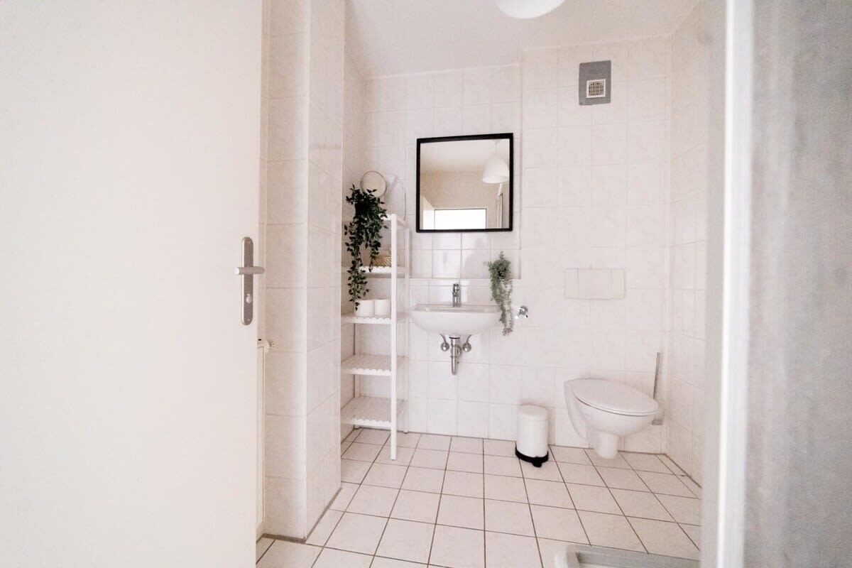Une petite salle de bain propre, avec un lavabo blanc, des toilettes et un miroir au-dessus du lavabo.