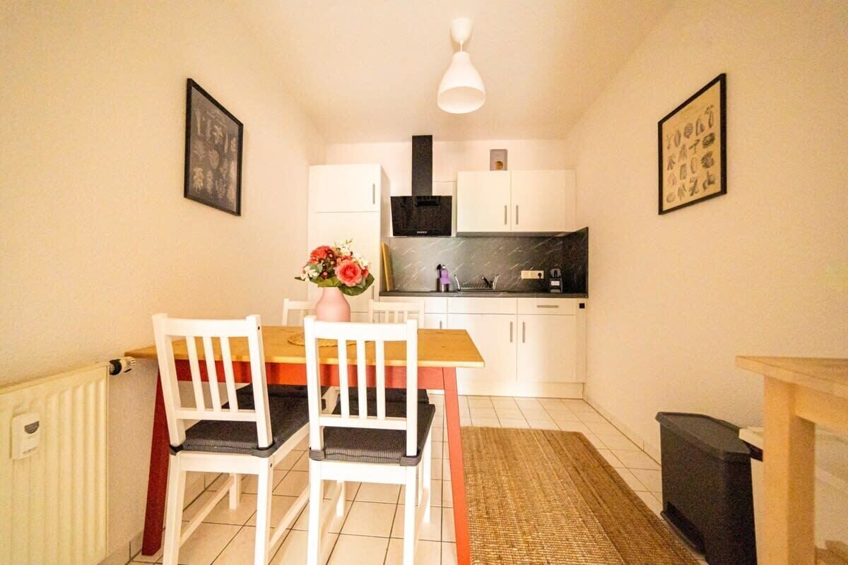 A compact kitchen with white cabinets, a black microwave, and a wooden dining table with two chairs.