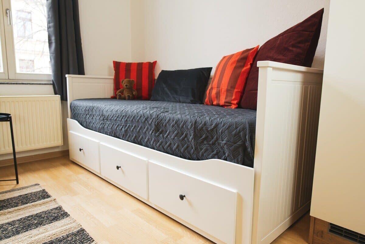 A bedroom with a bed, a teddy bear, and a radiator.