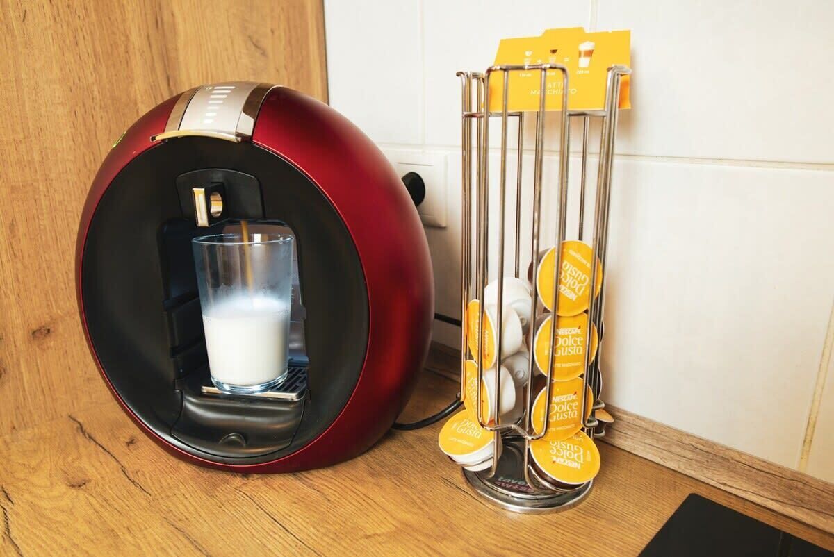 Une machine à café avec un verre de lait et un support pour les capsules de café.