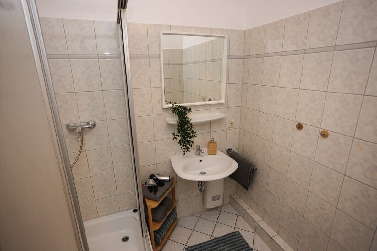 A bathroom with a shower, sink, and mirror.
