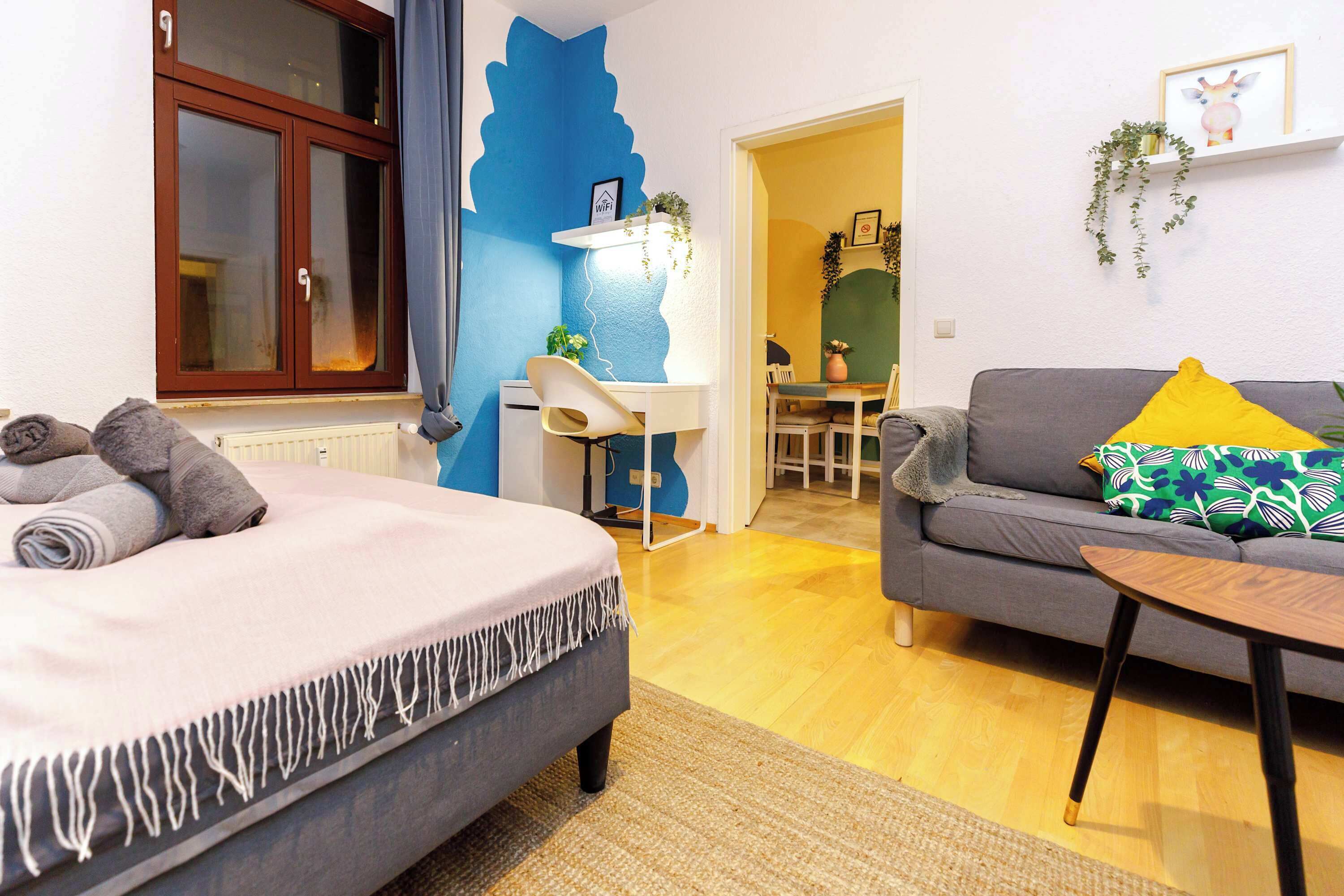 A bedroom with a bed, a desk, and a sofa.