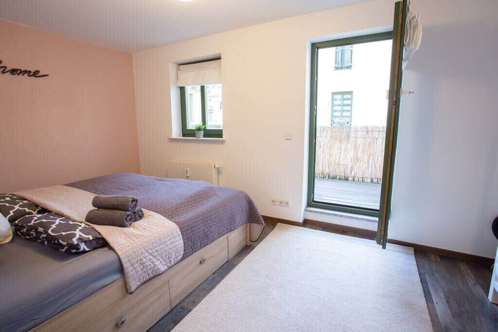 Een slaapkamer met een bed, een raam en een deur die uitkomt op een buitenruimte.