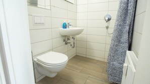 Une petite salle de bain avec des toilettes, un lavabo et une douche.