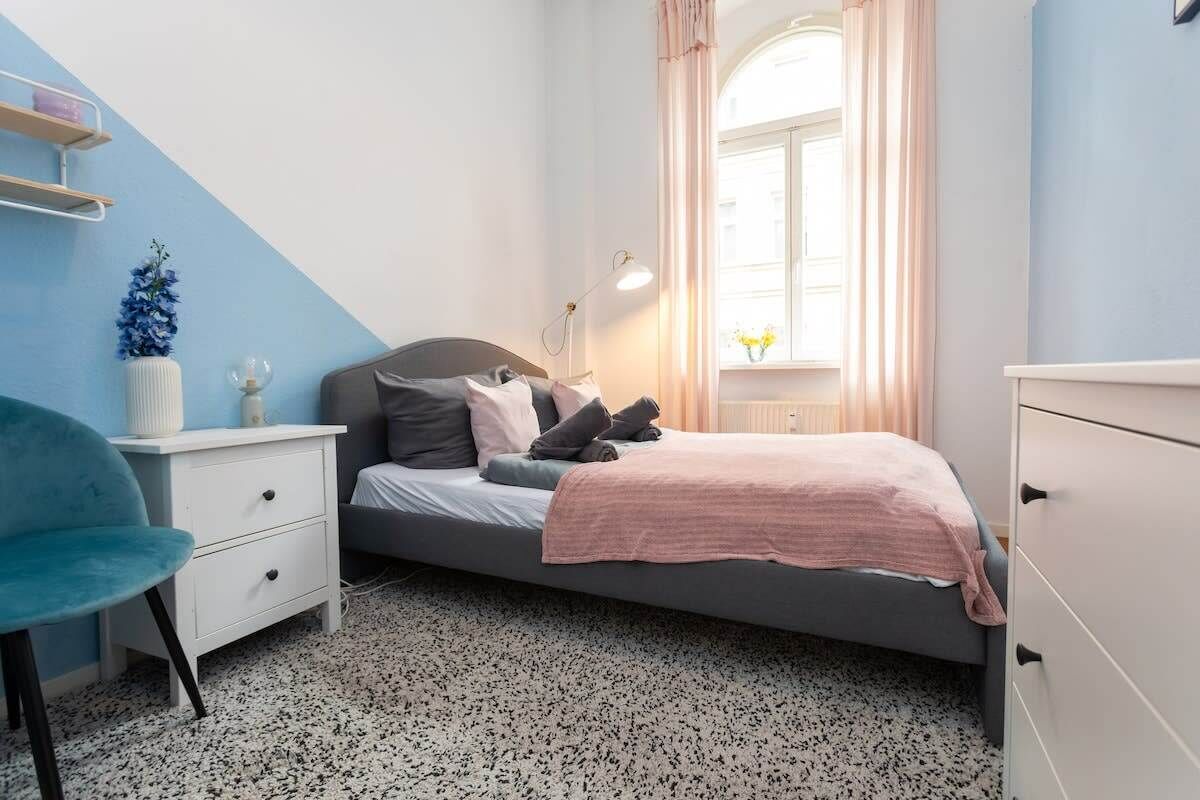 Una camera da letto con un letto, un comodino, una sedia e una finestra con tende.