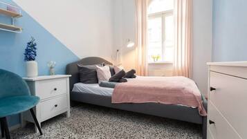 Una camera da letto con un letto, un comodino, una sedia e una finestra con tende.