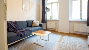 Un salon moderne avec un canapé gris, une table basse en bois et un tapis à motifs.
