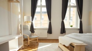 Ein modernes Schlafzimmer mit einem hölzernen Bett, einem Sessel, einem Schreibtisch und einem Fenster mit Vorhängen.