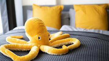 A plush octopus toy on a bed with a grey and yellow color scheme.