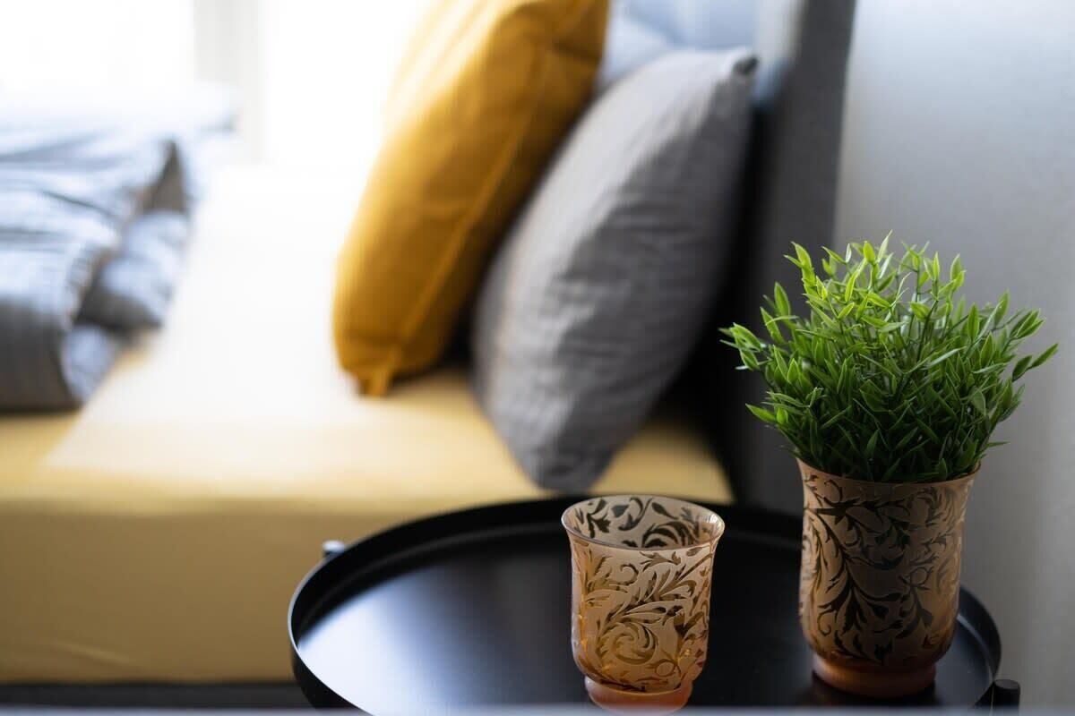 Une petite table sur laquelle sont posés un pot de fleurs et un verre décoratif.