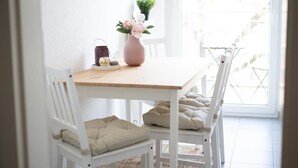 A dining area with a wooden table, white chairs, and a vase with flowers. - FullHouse | Chemnitz | HS46 | 3 Bedroom (Chemnitz)
